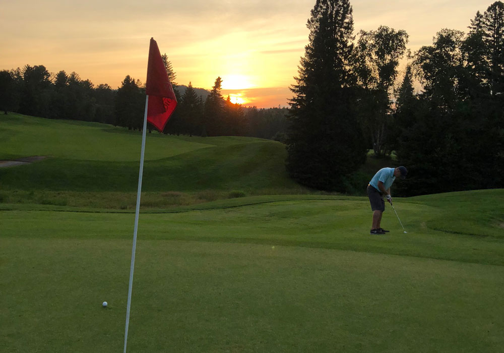 Joueur de golf sur le parcours du Club de golf Val‑Morin au coucher du soleil
